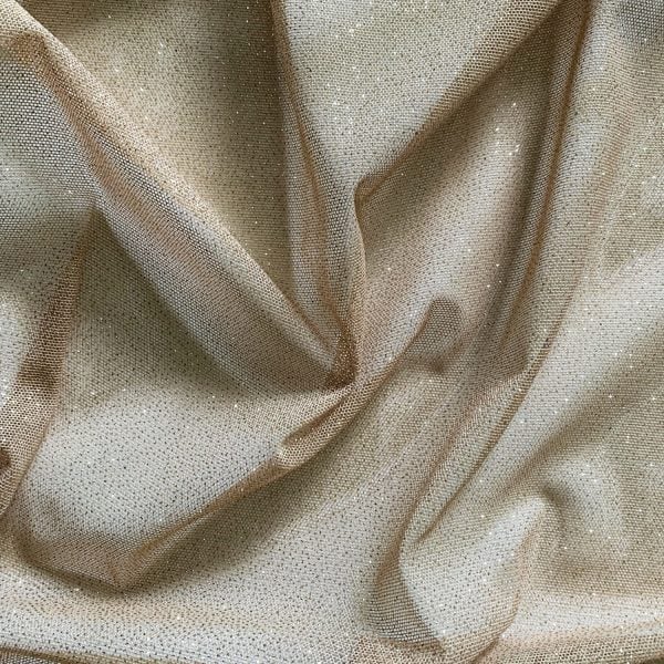 Nude Gold Glitter Mesh fabric features all over gold glitter on 2-way stretch nude polyester mesh making it ideal for both semi-fitted and draped garments.