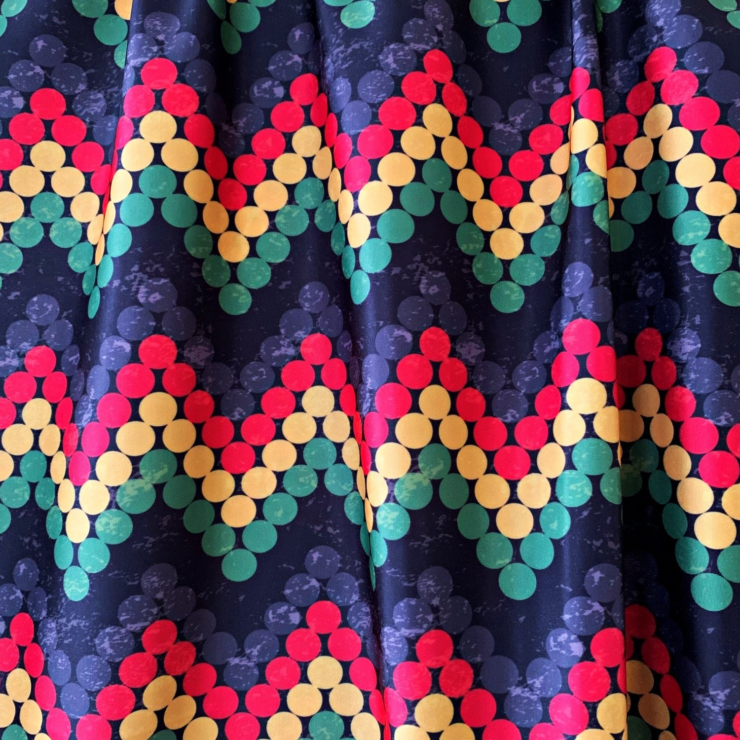 Rasta Print Fabric featuring red, yellow, green, grey and black dots in a zig zag repeating pattern